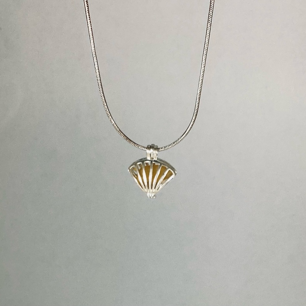 Amber sea glass necklace in silver seashell locket.